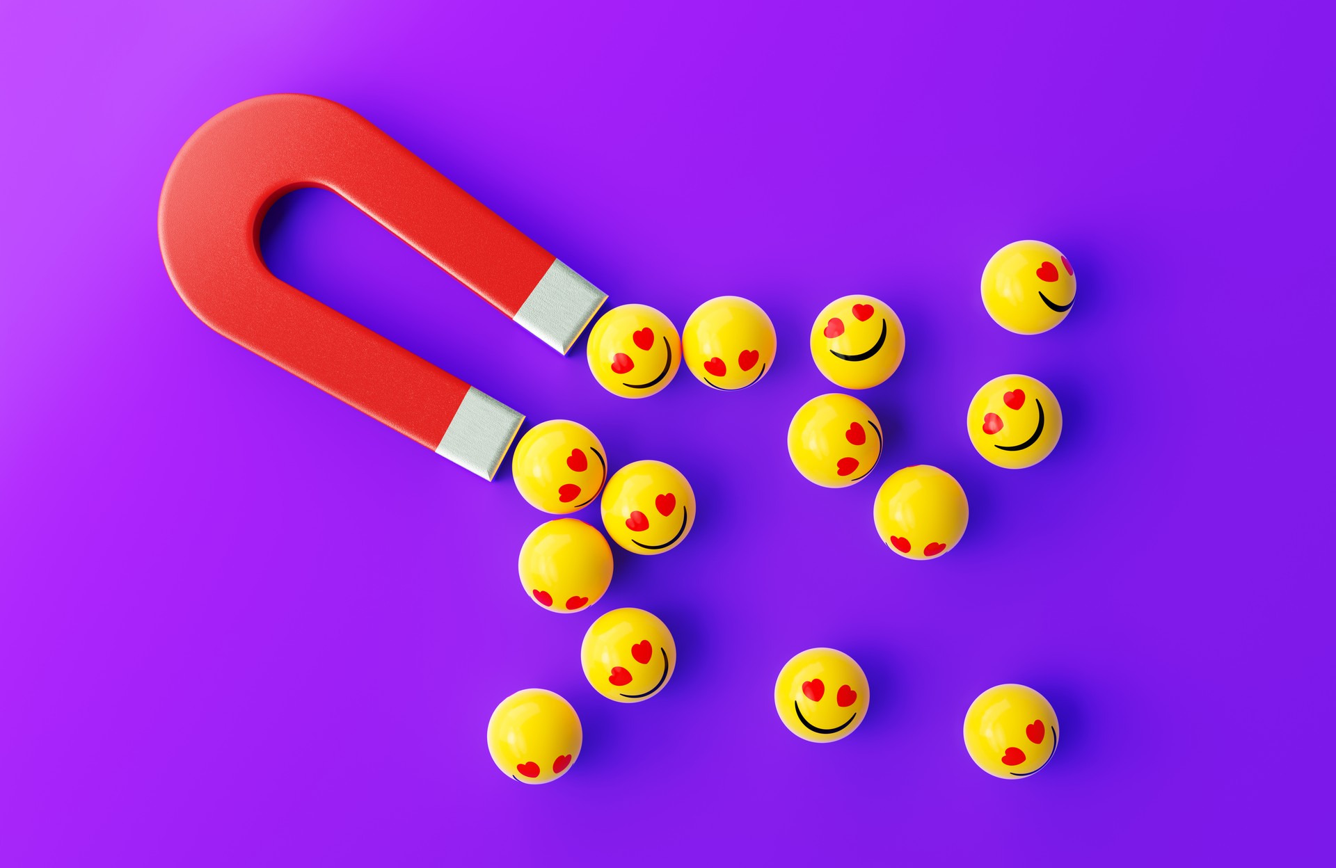 Sphères jaunes texturées avec un visage souriant Emoji sont attirées par un aimant rouge sur fond violet